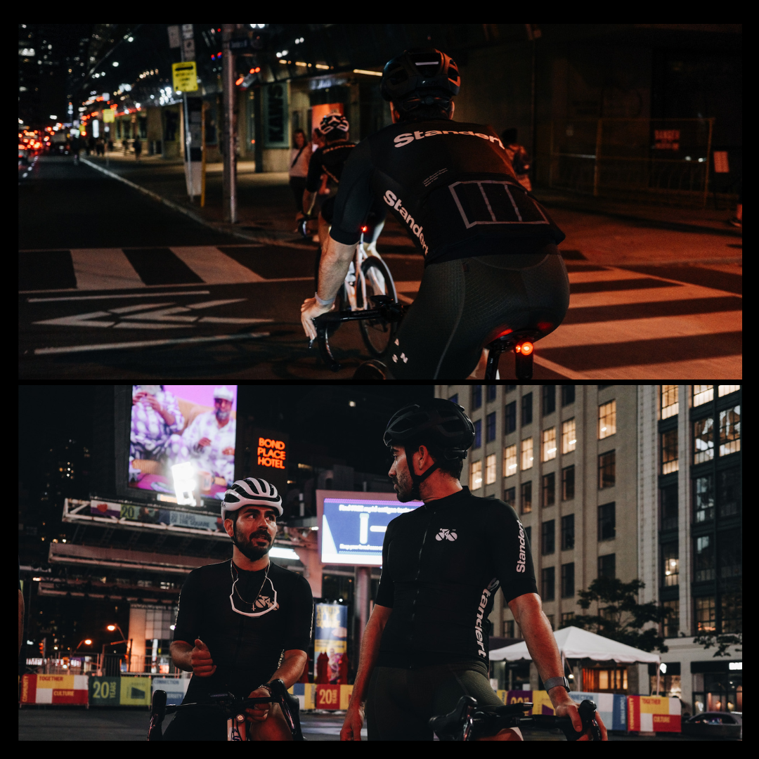 Split image: Top shows two cyclists riding on a city street at night. Bottom captures them stopped and talking on a city corner, with one cyclist gesturing. Bright signs and tall buildings in the background indicate an urban setting.