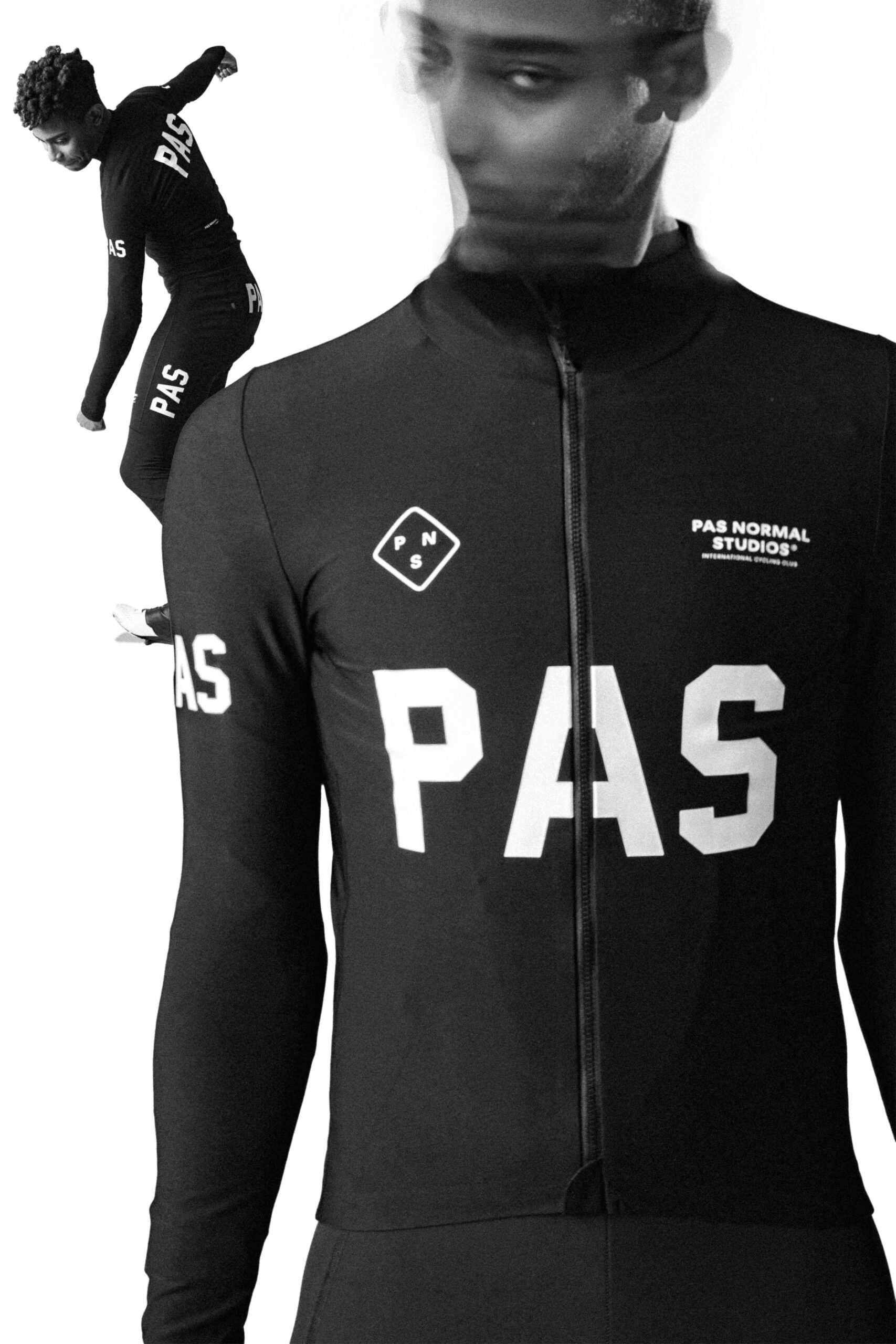 A person wearing a black bodysuit with "PAS" and "Pas Normal Studios" logos is shown. The image is blurred around the face. In the background, the same person is in motion, wearing the same suit. The photo has a high-contrast black-and-white style.